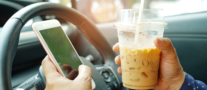 lady holding ice coffee and mobile phone in car