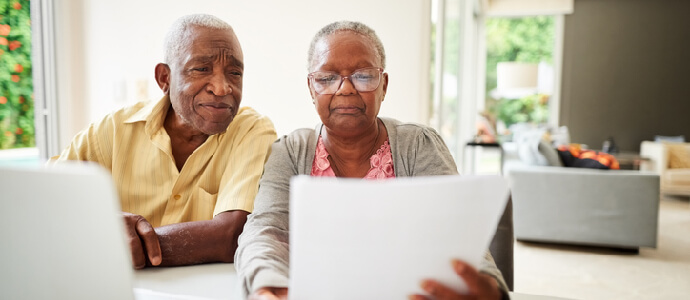 senior couple reading document with laptop at home, social security disability