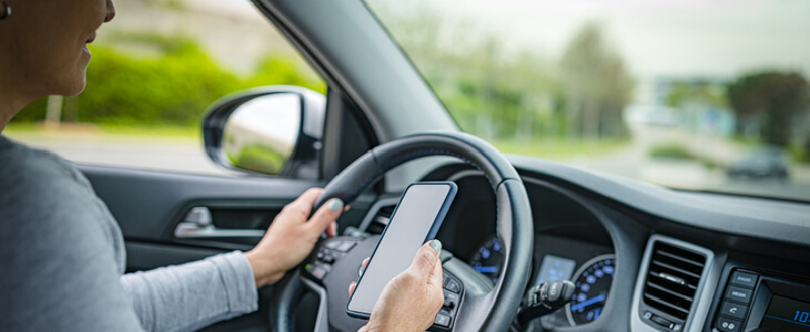 man driving his car recklessly while looking at his phone