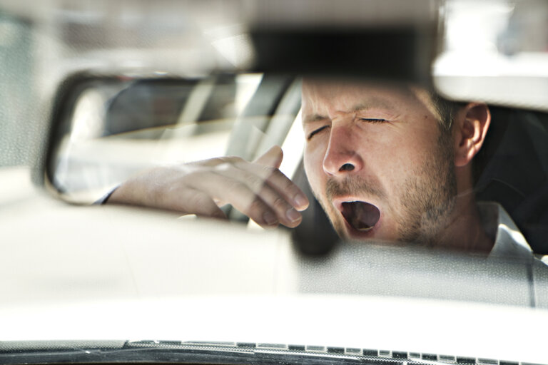 man yawning in the rearview mirror