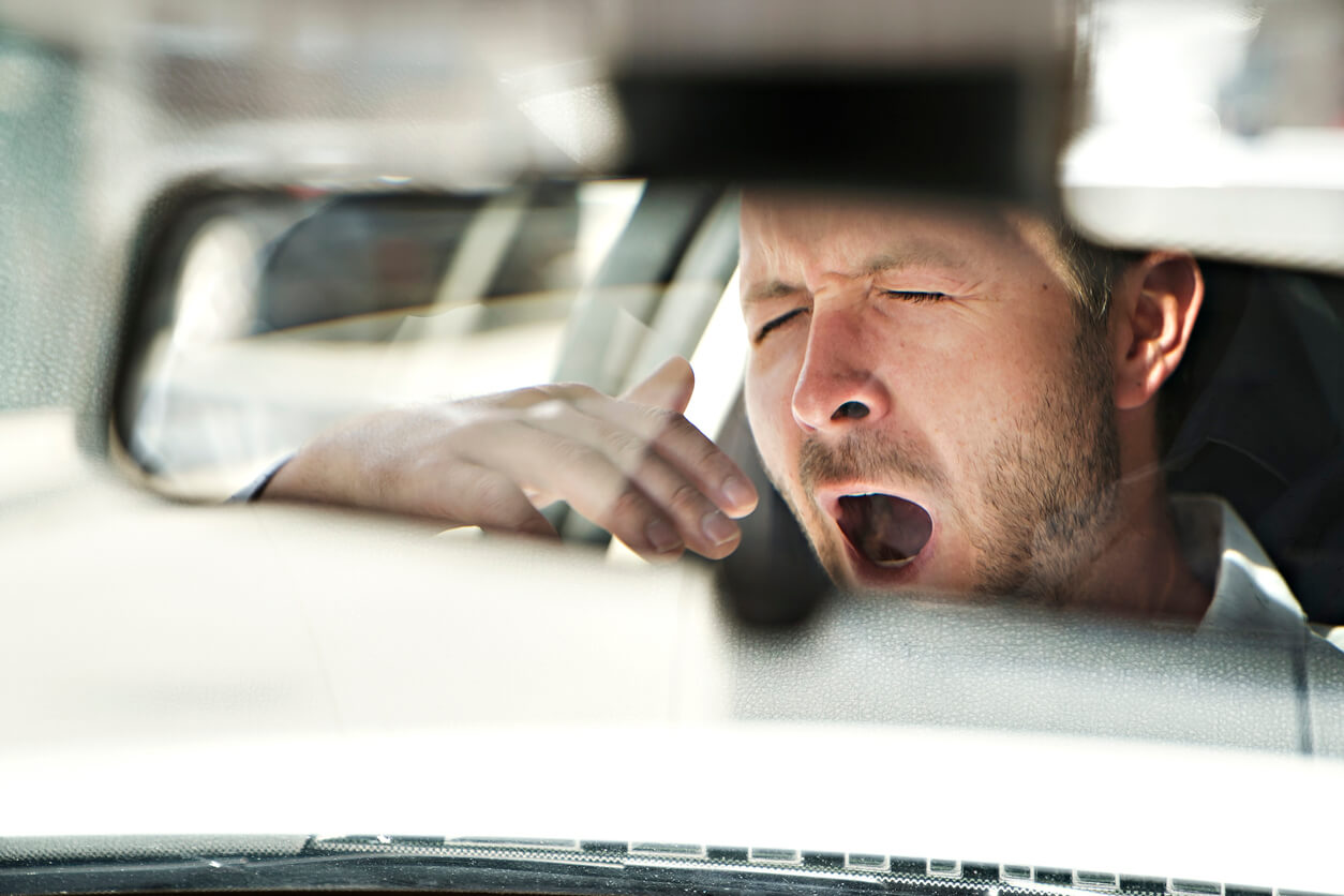 man yawning in the rearview mirror