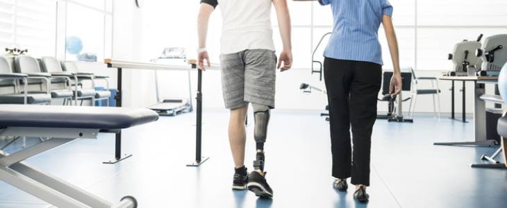 Amputee learning to walk with prosthetic leg.