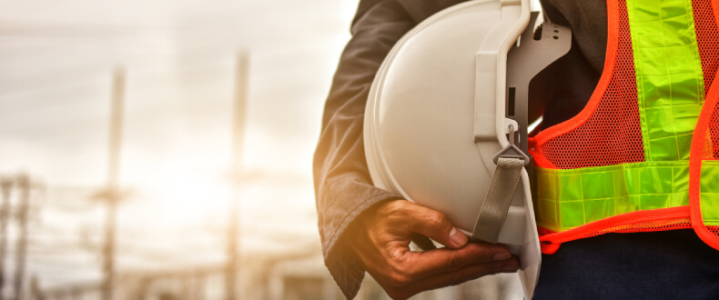 Construction work standing with his hard hat against his hip