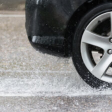 Close up of car's tire as it speeds through a wet road