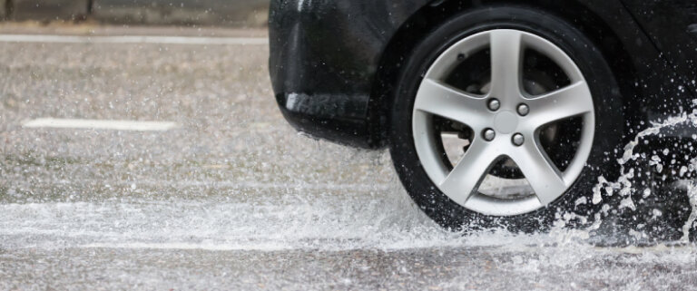 Close up of car's tire as it speeds through a wet road