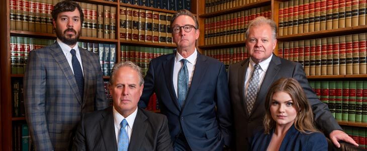 Group of lawyers in formal suits posing in law library with shelves of legal books