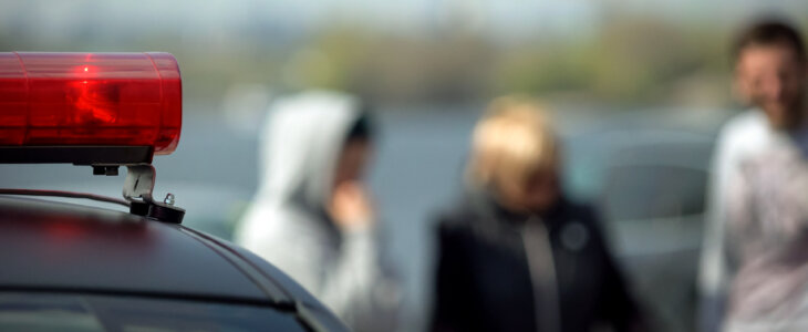 Red police siren light on car roof with blurred people in background