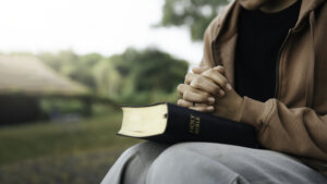 young person sitting outside with Bible