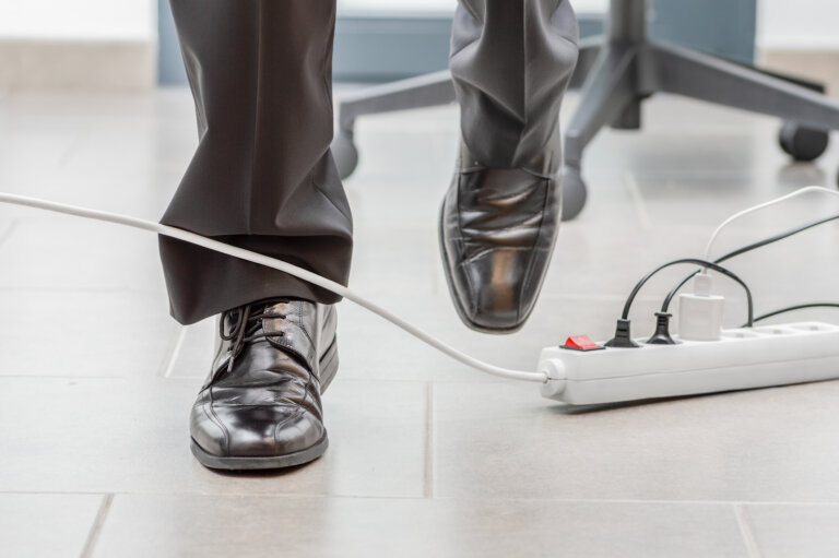 Close up of a businessman legs stumbling with an electrical cord