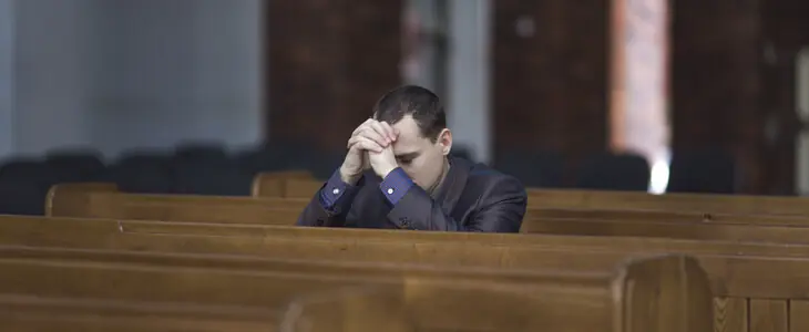 Christian man praying in a church pew