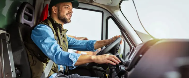 Man driving a delivery van, smiling with seatbelt on
